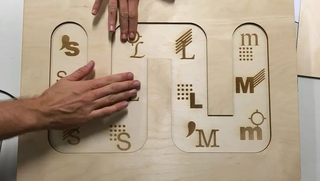 Hands touching a laser cut wooden box with etched letters on it